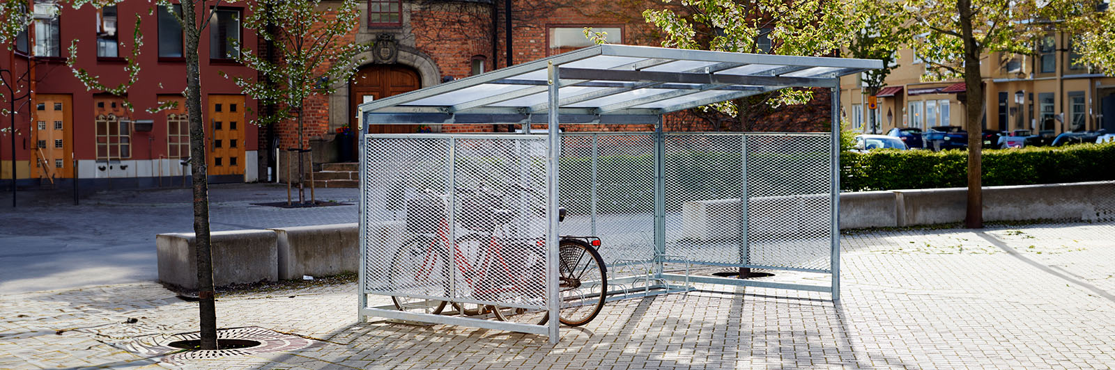 Large bicycle parking storage space in a street, surrounded by residential buildings.